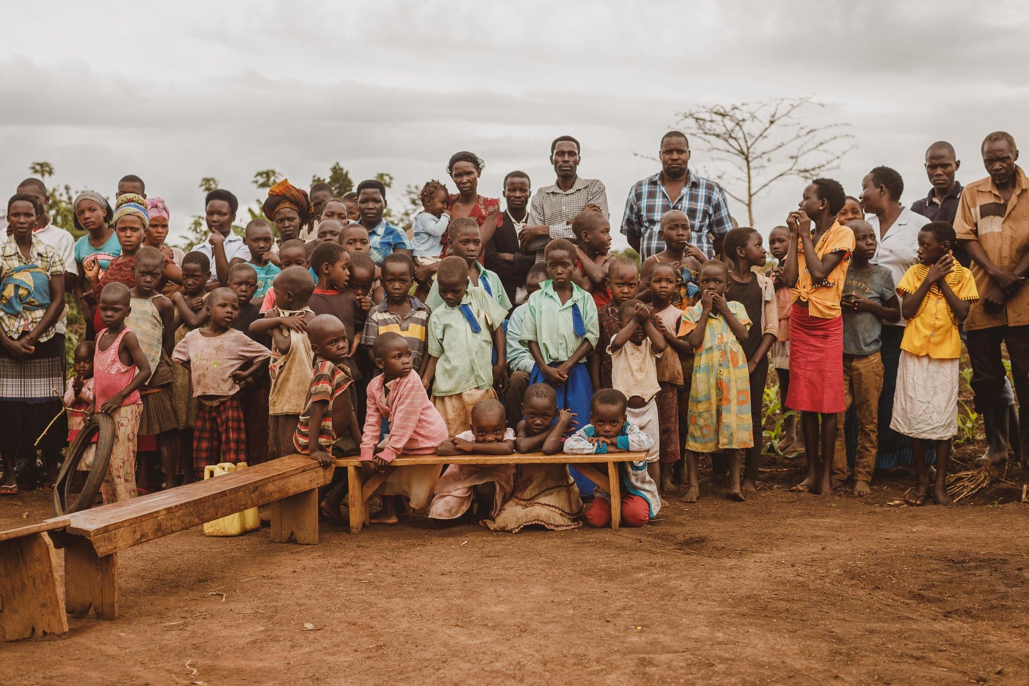A community gathered together outdoors in a rural village in Uganda