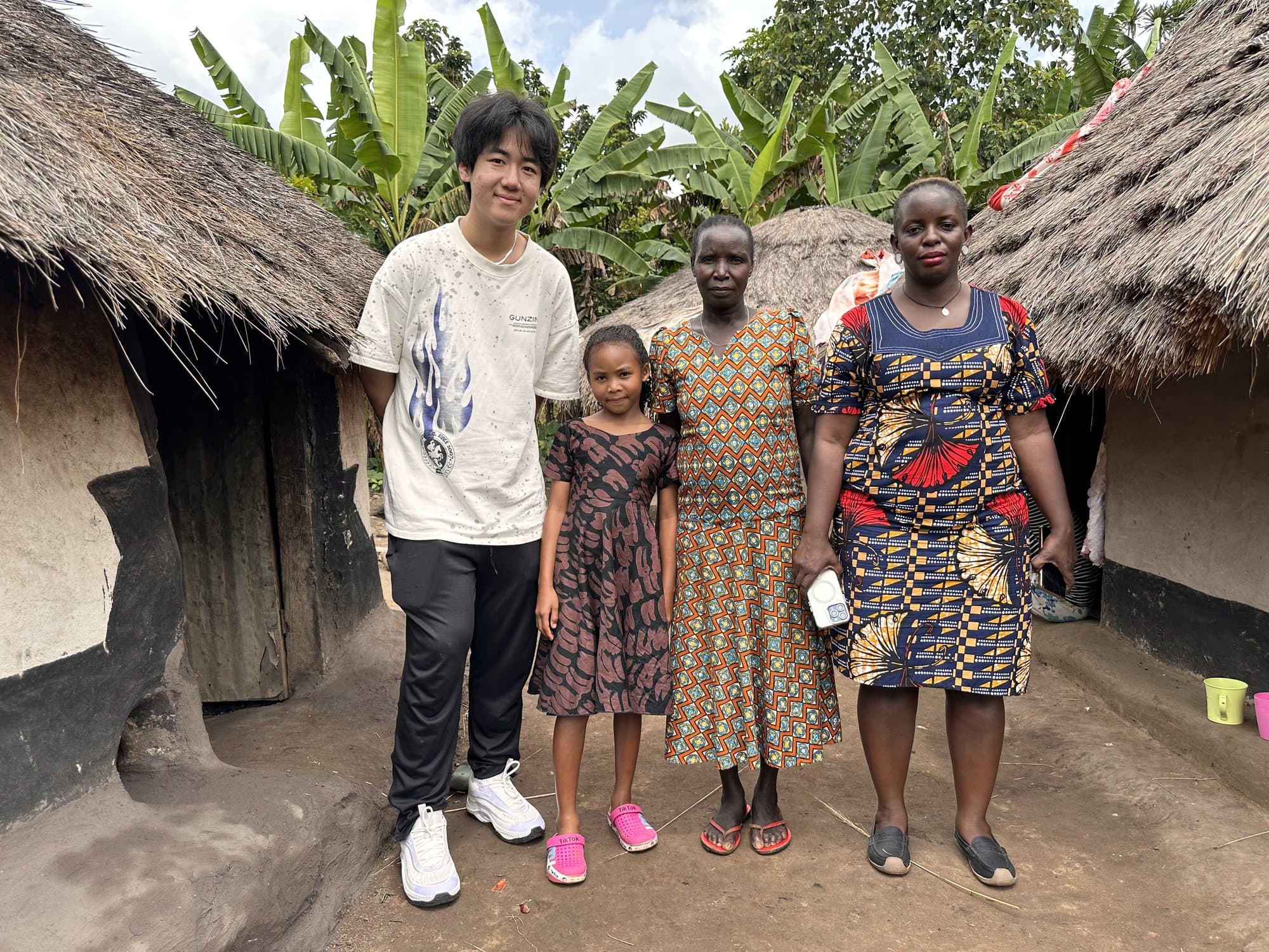 Eric Wang meeting with a Ugandan family outside their home